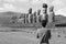 Monochrome image of massive Moai statues of Ahu Tongariki ceremonial platform with visitor in foreground, Easter island, Chile