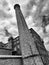 Monochrome image of an old stone mill buidlingin in Huddersfield West Yorkshire with a tall chimney against a dramatic sky