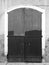 Monochrome image of old wooden closed doors on an empty derelict house with uneven paint