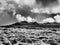 Monochrome image of rugged rocky outcrop tor on moorland hill with dark clouds rolling over, Dartmoor