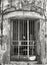 Monochrome image of rusted metal bars on the doorway of an old abandoned derelict building with cracked walls