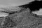 Monochrome infrared of rocky hills and mountains peaks with black sky and white clouds