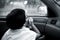 Monochrome portrait Asian girl sits in the car and looks out of window watching the rain and droplets