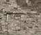 Monochrome sepia toned image of a large old wall made of mixed bricks and stone with many patched and uneven repairs