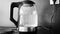 Monochrome video of close-up of boiling water in an electric kettle in the kitchen. Footage. Blue illuminated teapot