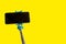 Monopod for selfie with smart phone. Selfie stick with smartphone isolated on yellow background