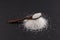 Monosodium glutamate Msg in a wooden spoon on a dark background. Food supplement E621. Taste seasoning to enhance the food