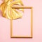 Monstera tropical plant leaf and frame painted gold pink background. Art concept minimalism. Vertical frame.