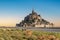 Mont Saint Michel abbey at sunrise, UNESCO world heritage site. Flock of sheep grazing in front of it.  Normandy, France.