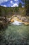 Montain river on a bed of yellow stones and dry grasses, flows into a river pool of crystalline waters, Sorradipara canyon,