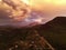 Montane forest with a road crossing by, a rural area and a cloudy sky at the sunset