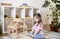 Montessori material. Child girl in pink T-shirt arranges wooden furniture in a doll house