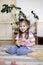 Montessori material. Child girl in pink T-shirt arranges wooden furniture in a doll house