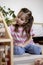 Montessori material. Child girl in pink T-shirt arranges wooden furniture in a doll house