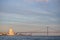 Monument of Discoveries surrounded by the sea and bridge with a plane above it during the sunset