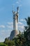 A monument with a high statue of the motherland with arms raised upwards holding a sword in another shield with Soviet