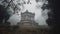 a monument in the middle of a forest on a foggy day with trees in the foreground and a few branches in the foreground