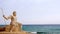 Monumental statue of God Poseidon on the beach, against the backdrop of the sea.