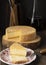 Moody brazilian Canastra artisanal cheese with slices over a wooden board with wine bottle