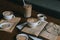 Moody close-up of a selection of coffee cups and cookies next to a book