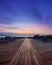 Moody empty boardwalk at dusk. Dramatic sunset with blue tones and wispy sweeping clouds