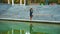 Moody girl walking in park and reflecting in lake water