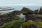 Moody grey arctic coast with sea view - slope of granite shore with smooth rocks  and lush green meadow, Barents Sea in haze.