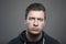 Moody headshot portrait of young upset man looking at camera