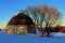 Moody Lake Barn near Chisago City, Minnesota round blue barn near a lake with trees and a fence in Winter in an orange glow