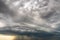 Moody landscape with dark stormy clouds with falling heavy downpour shower rain in summer