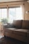 Moody living room with couch by window. Sunlight shines on sofa.