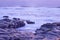 Moody Ocean Seascape landscape on rocky beach with purple hue