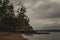 Moody photo of a rocky cliff at the edge of a sandy beach on a stormy evening