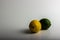 A moody photograph of a delicious yellow lemon and green lime against a white background.