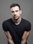 Moody portrait of fit muscular serious man wearing blank black t-shirt looking at camera suspiciously