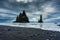 Moody Reynisdragar natural rock formation on Reynisfjara black sand beach in Atlantic ocean at Iceland