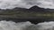 Moody sky over mountain peaks reflecting in lake surface