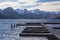 moody waterfront wooden dock pier for boats and mountains snowy peaks background scenic view in rainy foggy weather