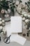 Moody wedding table mockup scene. Stationery composition with fading white rose flowers, silver plate, post stamps