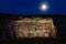 Moon over illuminated limestone cliff