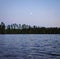 Moon rise over the lake and pine forest. Moonlight reflection in the waves water surface