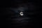 Moon rising against black sky with clouds at night