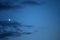 The moon showing against blue sky with clouds