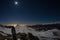 Moon and starry sky, snow on the Alps, fisheye lens. Orion Constellation, Betelgeuse and Sirio. Long exposure blurred two hikers l