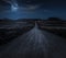 Moon, stars and clouds in the night. Wild west road illuminated from the moon. Moonlight and road background