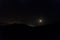 Moonlight illuminating horizontal mountain silhouette with starry sky