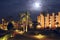 Moonlight illuminating tropical resort with hotel building and palm trees at night