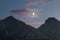 Moonlight in the mountains. Crescent moon in the sunset sky, pink clouds