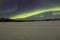 Moonlight over frozen lake under northern lights