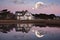 moonrise over cape cod house with reflection in water